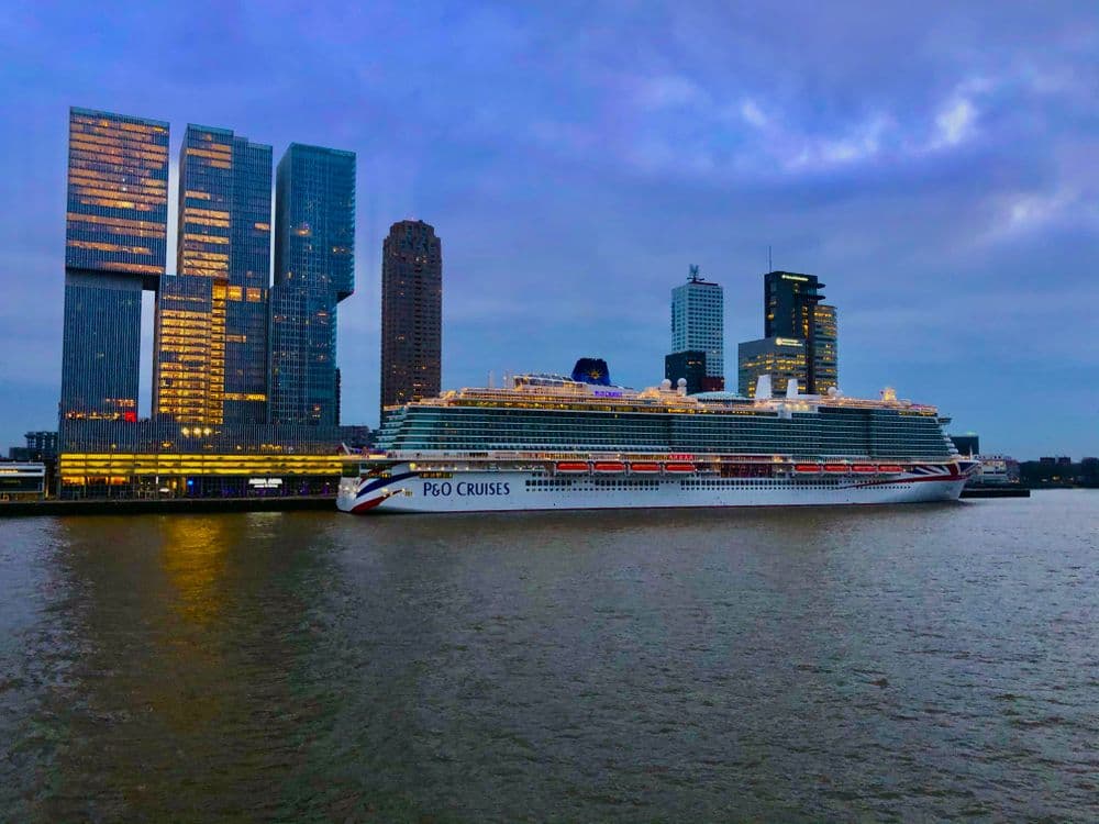 A modern cruise ship sailing on calm ocean waters at dusk