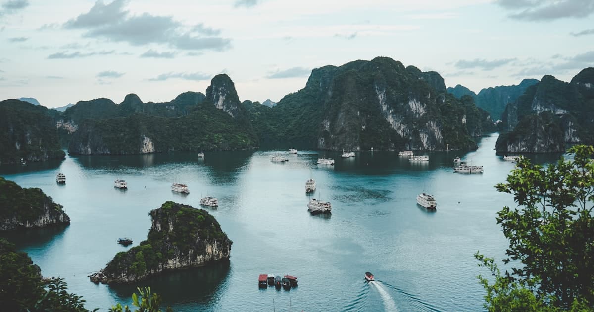 Traditional Vietnamese boats floating on a misty river surrounded by limestone karsts in Ha Long Bay