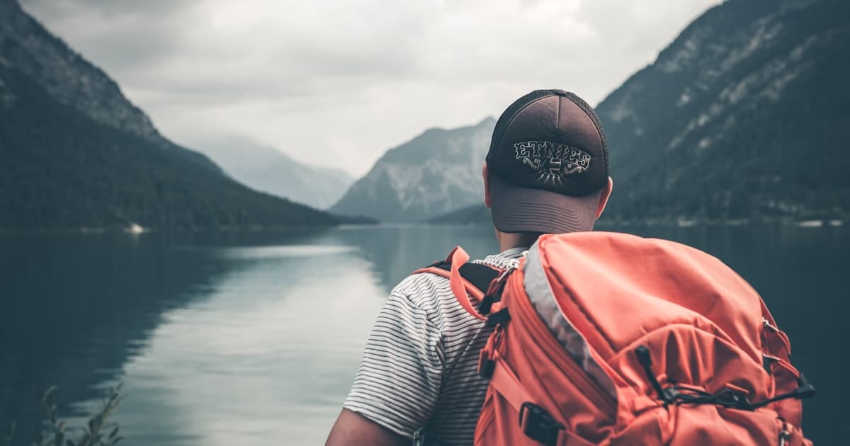 A solo traveler with a backpack gazes at misty mountains from a scenic overlook at sunrise